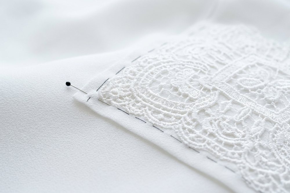 Empiècement de dentelle posé sur du crêpe blanc.