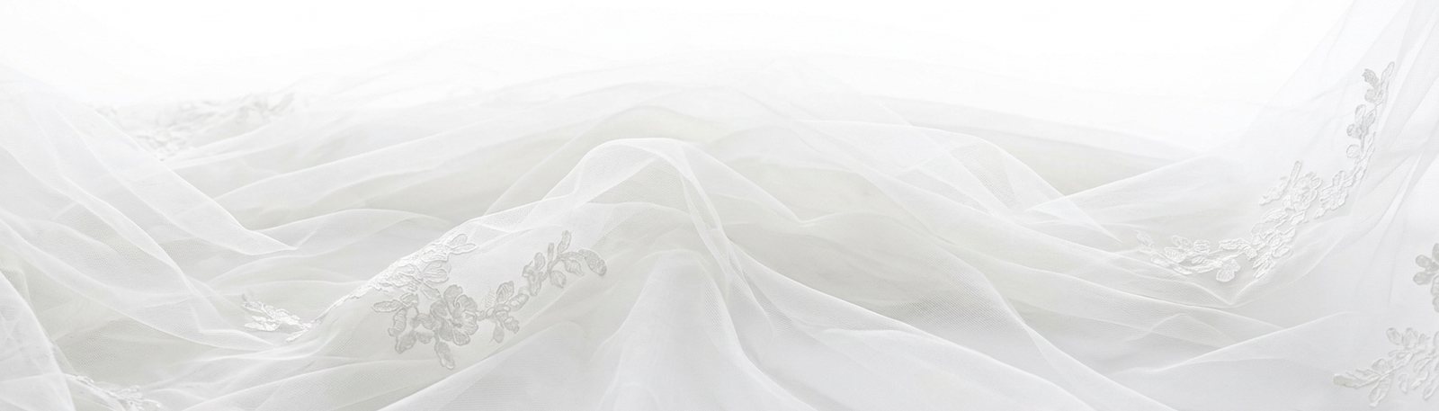 Voile de mariée très long étalé, ses plis créant des variations de blanc.