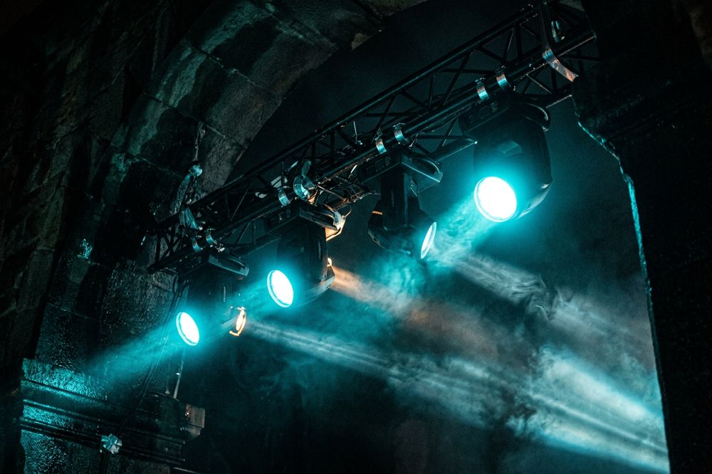 Projecteurs asservis accrochés à une structure, allumés en cyan.