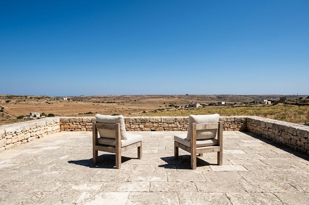 La terrasse en dalles de pierre ouverte sur la vallée, chaises vides.