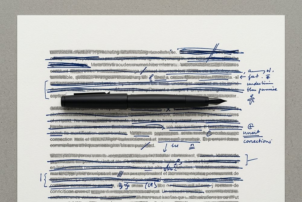 Un stylo plume posé sur un texte corrigé à l’encre bleue